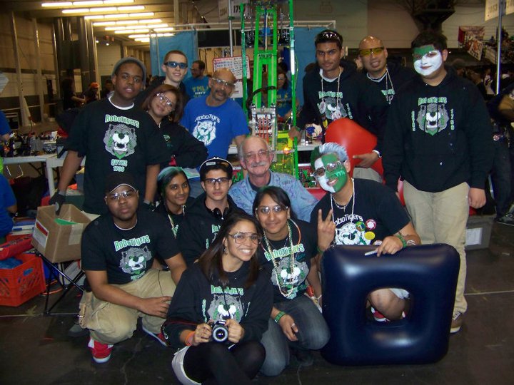 Dr. Woodie Flowers posing with RoboTigers Team 1796 students in a competition pit